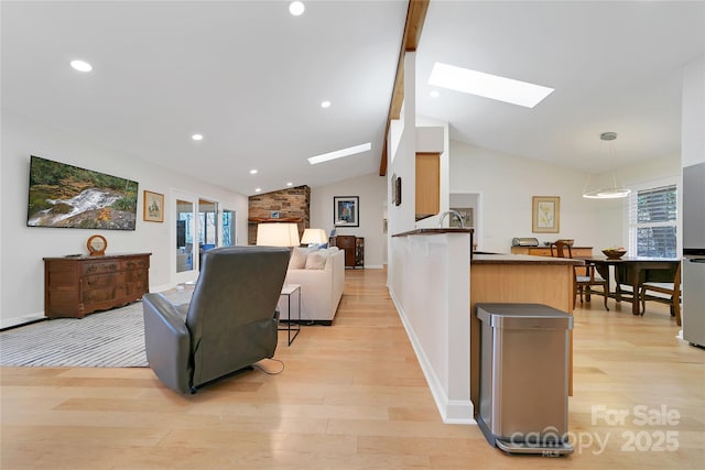living room with a skylight, light wood-style flooring, recessed lighting, and baseboards