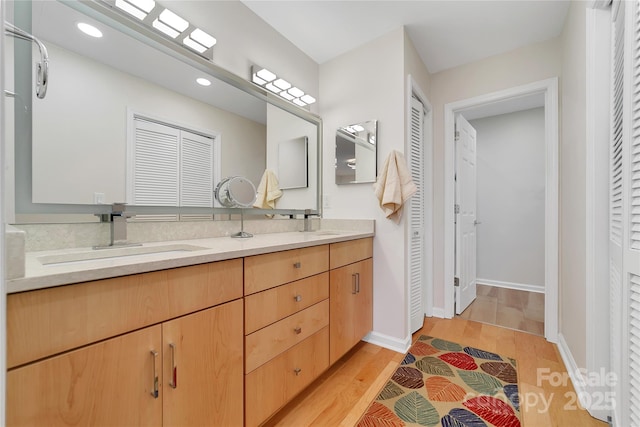 full bath featuring a closet, double vanity, recessed lighting, wood finished floors, and baseboards