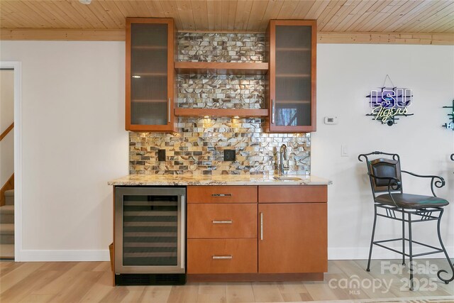 indoor wet bar featuring beverage cooler, wood ceiling, backsplash, stairway, and light wood-style flooring