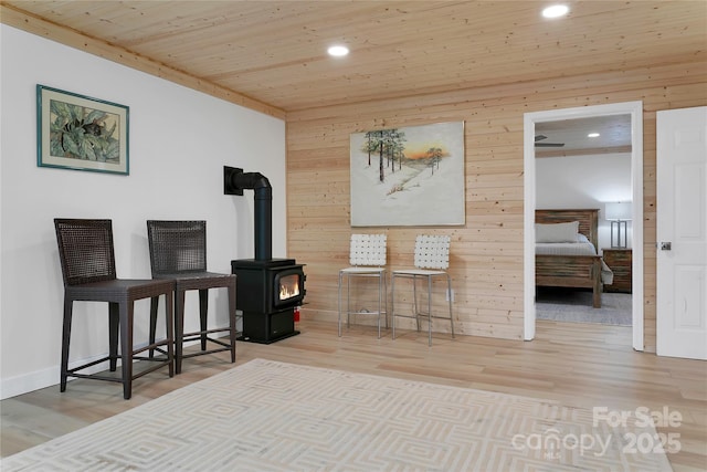 sitting room with a wood stove, wood finished floors, recessed lighting, wooden walls, and wooden ceiling