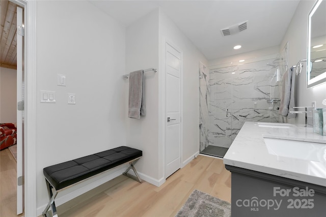 full bath with wood finished floors, a marble finish shower, double vanity, baseboards, and recessed lighting