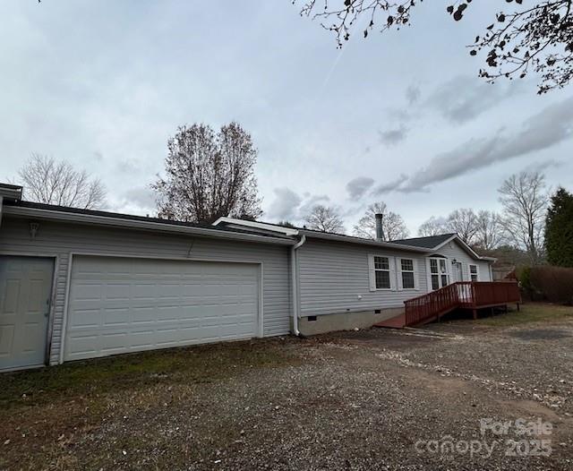 view of side of home featuring a garage and a wooden deck