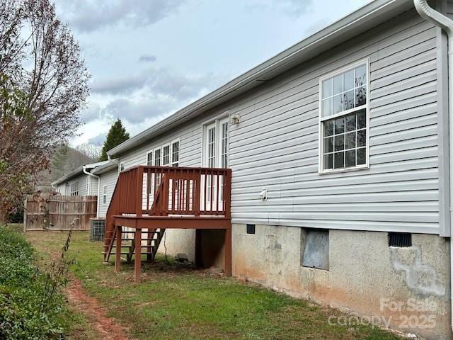 view of side of property featuring central air condition unit, a yard, and a wooden deck