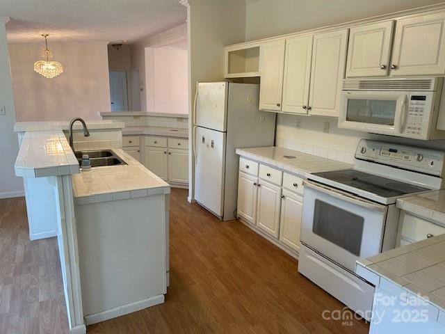 kitchen featuring white appliances, tile countertops, decorative light fixtures, and white cabinetry