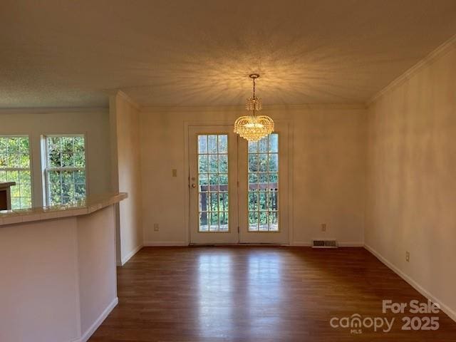 interior space featuring ornamental molding, a notable chandelier, and dark wood-type flooring