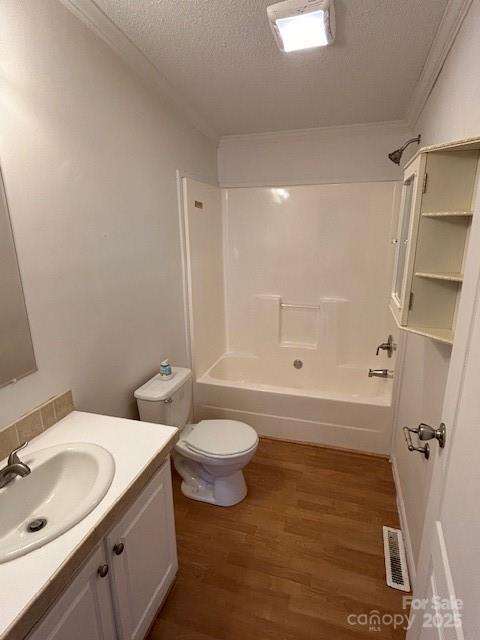 full bathroom with toilet, wood-type flooring, crown molding, vanity, and a textured ceiling