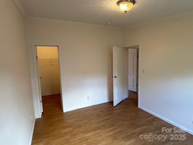 unfurnished room with a textured ceiling, crown molding, and hardwood / wood-style floors