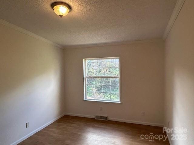 spare room with a textured ceiling, dark hardwood / wood-style flooring, and crown molding