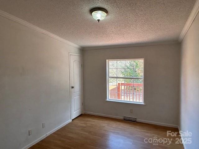 unfurnished room featuring a textured ceiling, crown molding, and hardwood / wood-style floors