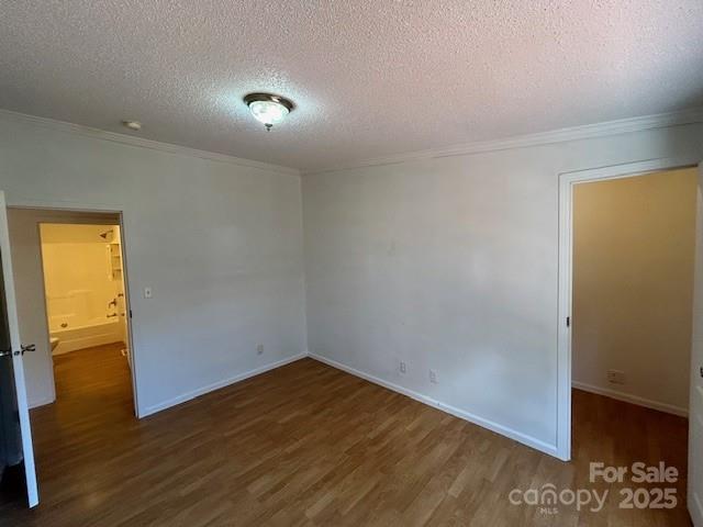 unfurnished room with a textured ceiling, dark wood-type flooring, and crown molding