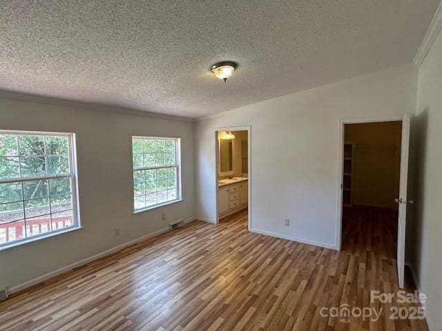 spare room featuring a textured ceiling, vaulted ceiling, light hardwood / wood-style flooring, and plenty of natural light