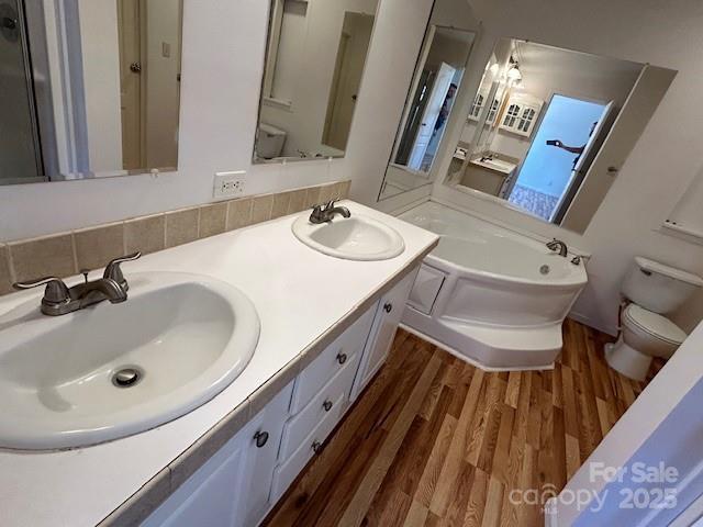 bathroom with hardwood / wood-style floors, tasteful backsplash, a bathing tub, toilet, and vanity