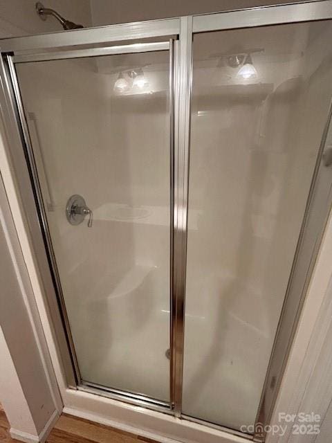 bathroom with a shower with door and wood-type flooring