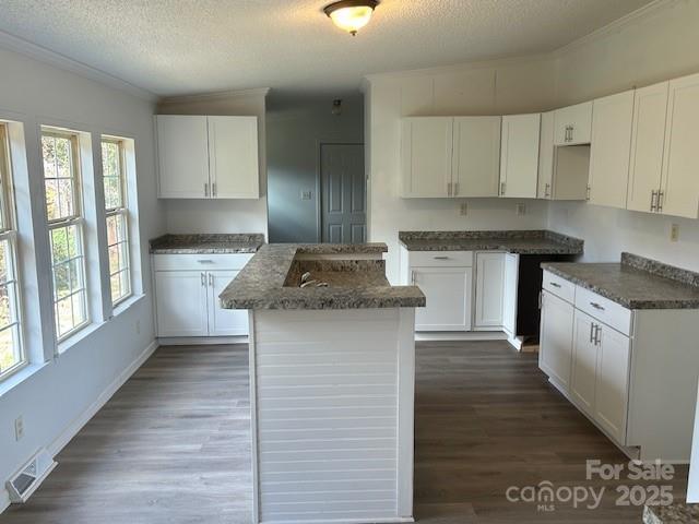 kitchen featuring white cabinets, a center island, a textured ceiling, and dark wood-type flooring