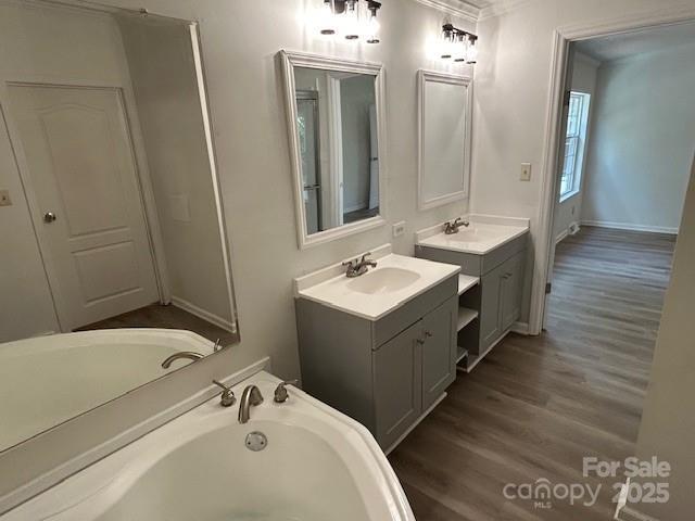 bathroom with a bath, crown molding, vanity, and hardwood / wood-style flooring