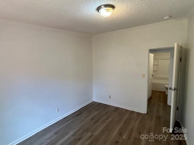 spare room with a textured ceiling and dark hardwood / wood-style floors