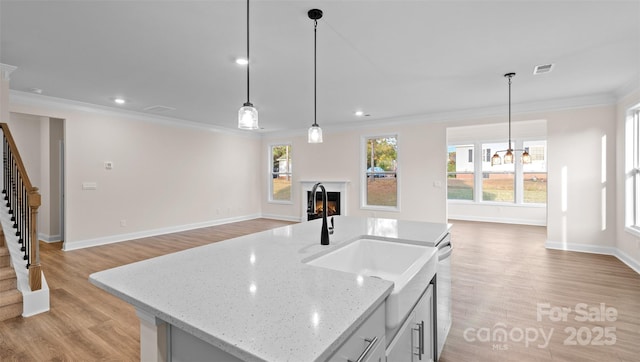 kitchen featuring light stone countertops, pendant lighting, dishwasher, and a center island with sink