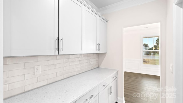 interior space featuring light stone counters, crown molding, backsplash, and white cabinetry