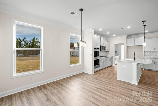 kitchen with stainless steel appliances, an island with sink, decorative backsplash, and pendant lighting