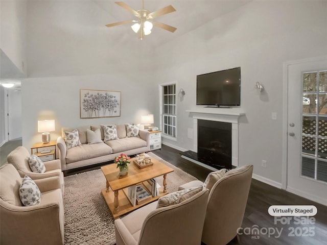 living room featuring a towering ceiling, dark hardwood / wood-style flooring, and ceiling fan