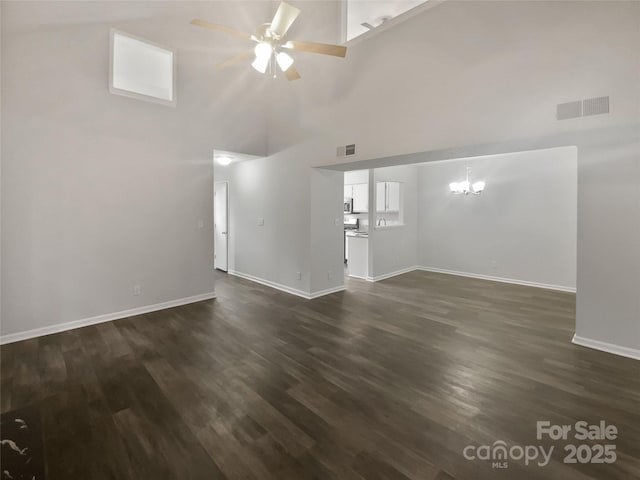 unfurnished living room with a high ceiling, dark hardwood / wood-style flooring, and ceiling fan with notable chandelier