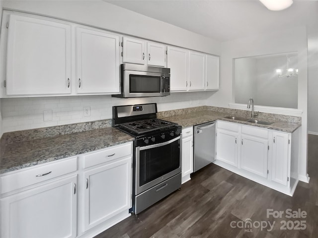 kitchen with a chandelier, appliances with stainless steel finishes, dark wood-type flooring, white cabinets, and sink