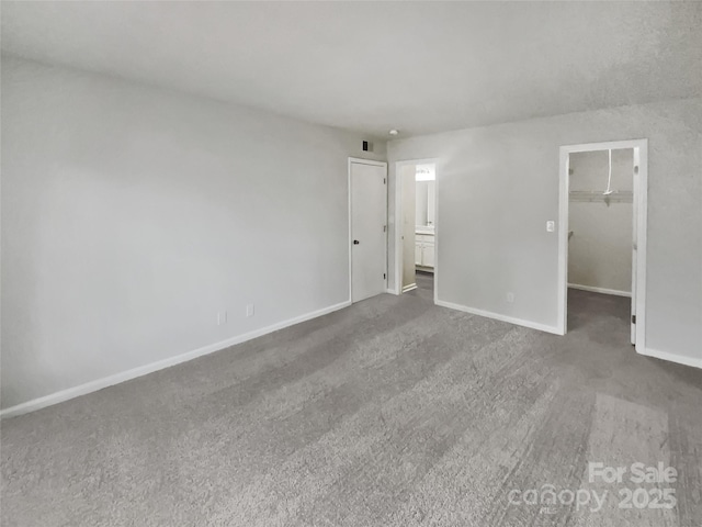 unfurnished bedroom with a spacious closet, a closet, and carpet