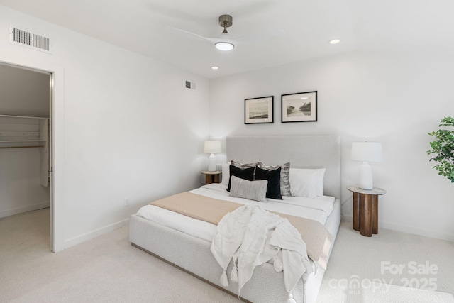 bedroom with light carpet, ceiling fan, a closet, and a spacious closet