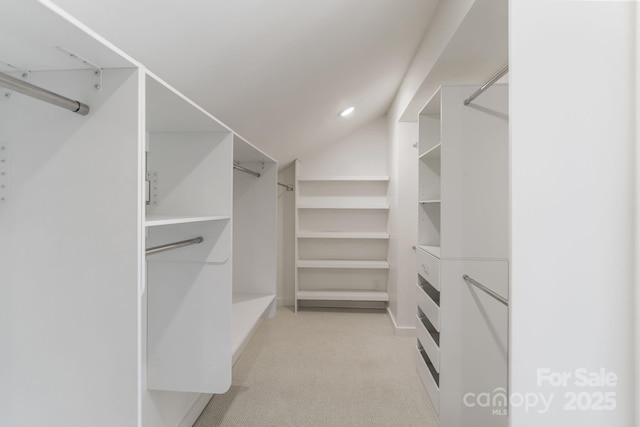 walk in closet featuring light carpet and vaulted ceiling