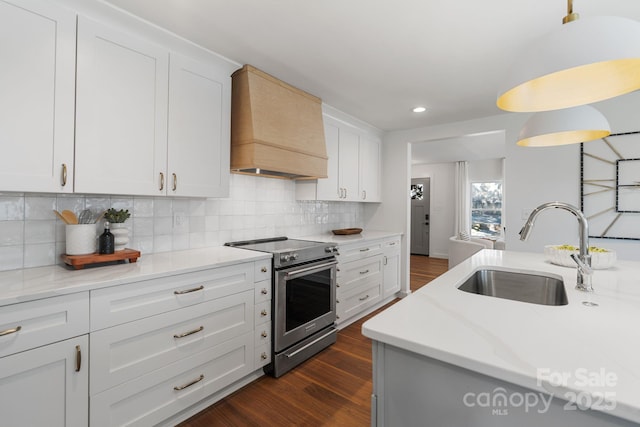 kitchen featuring tasteful backsplash, premium range hood, sink, stainless steel electric stove, and white cabinets