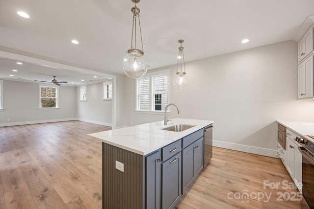 kitchen featuring a center island with sink, a sink, recessed lighting, stainless steel appliances, and light wood finished floors