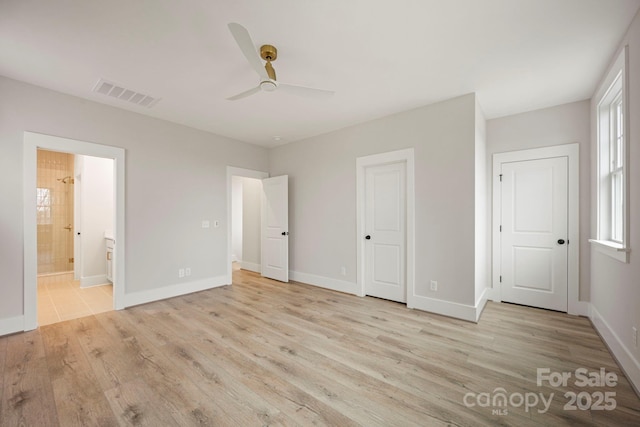 unfurnished bedroom featuring visible vents, ensuite bathroom, baseboards, and wood finished floors