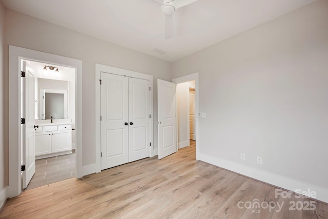 unfurnished bedroom with baseboards, ensuite bathroom, and light wood finished floors