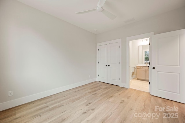 unfurnished bedroom featuring a closet, light wood-style flooring, ensuite bath, and baseboards