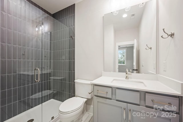 bathroom with visible vents, vanity, a shower stall, and toilet