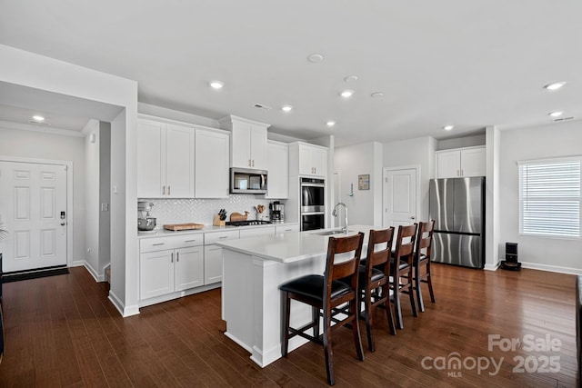 kitchen featuring appliances with stainless steel finishes, white cabinets, and a center island with sink