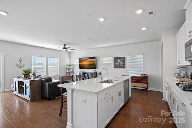 kitchen with white cabinetry, an island with sink, sink, dark hardwood / wood-style floors, and a breakfast bar area