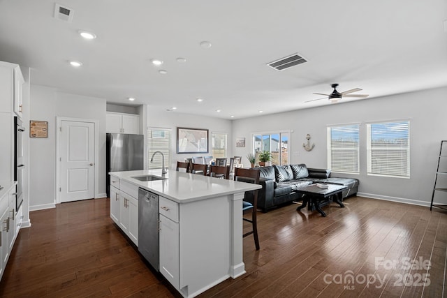 kitchen with a breakfast bar area, stainless steel appliances, a kitchen island with sink, white cabinets, and sink