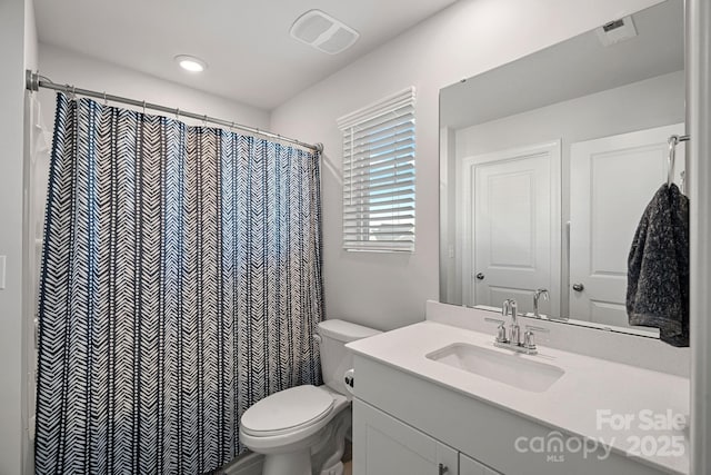 bathroom featuring toilet, a shower with shower curtain, and vanity