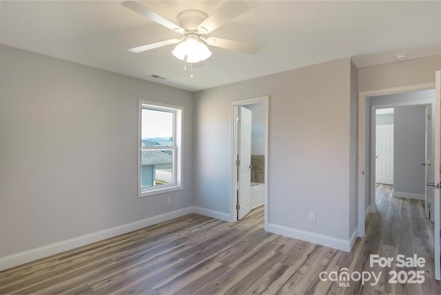 unfurnished bedroom featuring wood-type flooring, ensuite bathroom, and ceiling fan