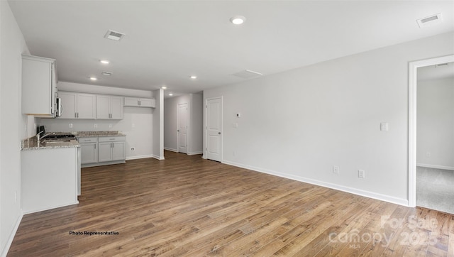 kitchen featuring light stone counters, white cabinetry, range, and hardwood / wood-style floors