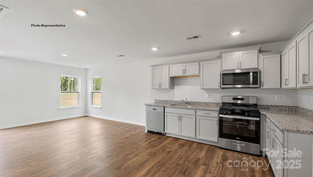 kitchen featuring light stone countertops, appliances with stainless steel finishes, dark hardwood / wood-style flooring, and sink