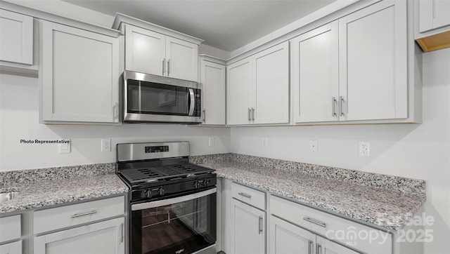 kitchen with light stone counters, white cabinets, and appliances with stainless steel finishes