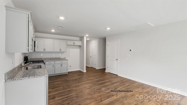 kitchen with sink, white cabinetry, dark wood-type flooring, light stone countertops, and range