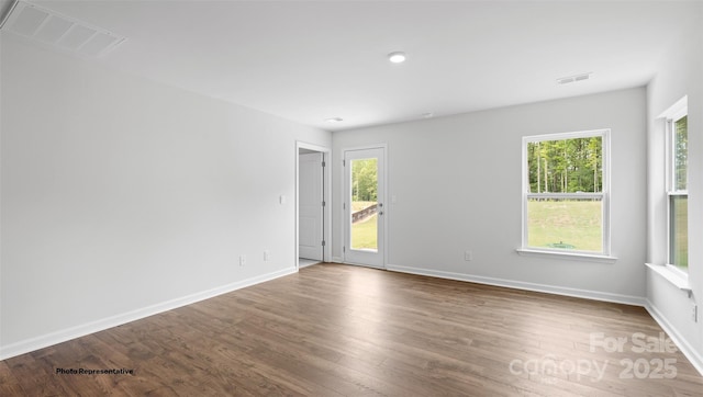 unfurnished room featuring a wealth of natural light and hardwood / wood-style floors