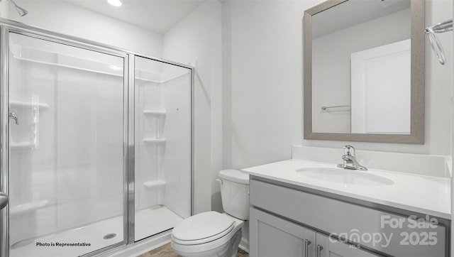 bathroom with a shower with shower door, toilet, and vanity