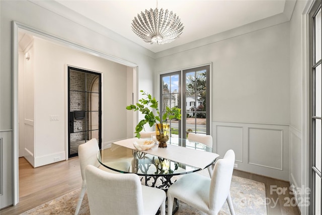 dining area featuring ornamental molding, a notable chandelier, and light hardwood / wood-style floors