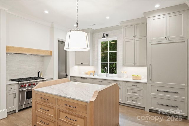 kitchen featuring high end range, a center island, pendant lighting, decorative backsplash, and light hardwood / wood-style flooring