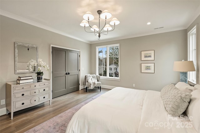 bedroom featuring hardwood / wood-style flooring, an inviting chandelier, and crown molding