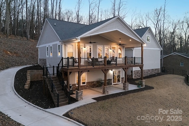 back house at dusk featuring ceiling fan, a porch, and a patio